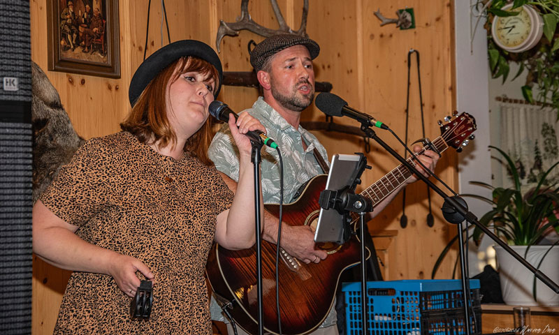 Jana und Danny gemeinsam auf der Bühne mit Mikrofonen und Gitarre während Danny singt