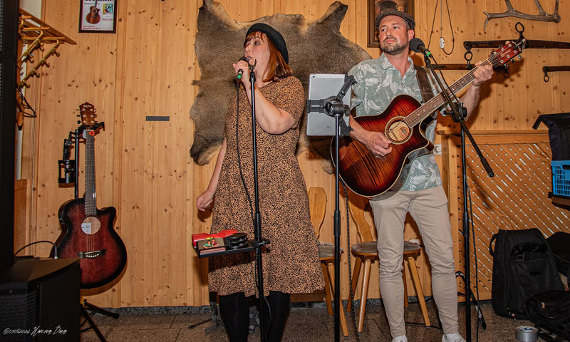Jana und Danny gemeinsam auf der Bühne mit Mikrofonen und Gitarre während Jana singt